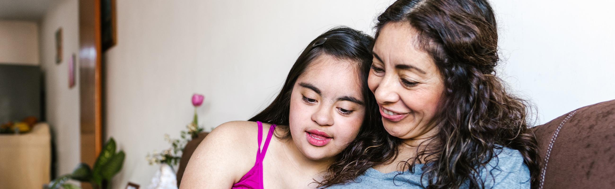a daughter leans against her mother while they read a book