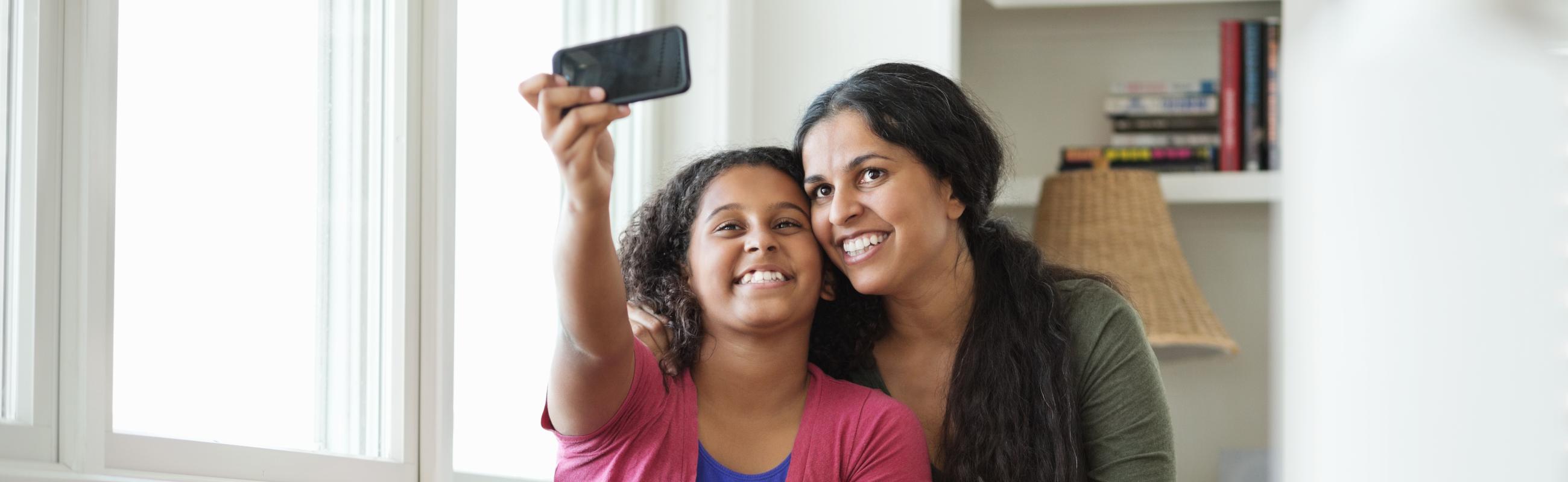 a daughter and mother smile while looking at a camera