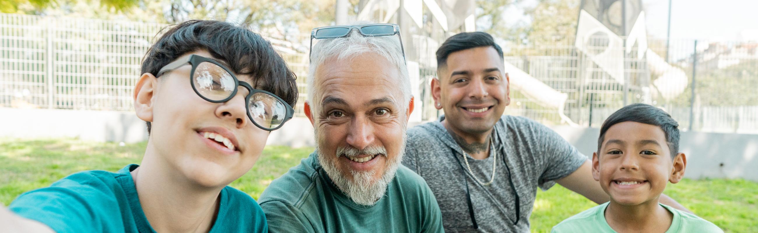 two boys sit with their dads outside a park