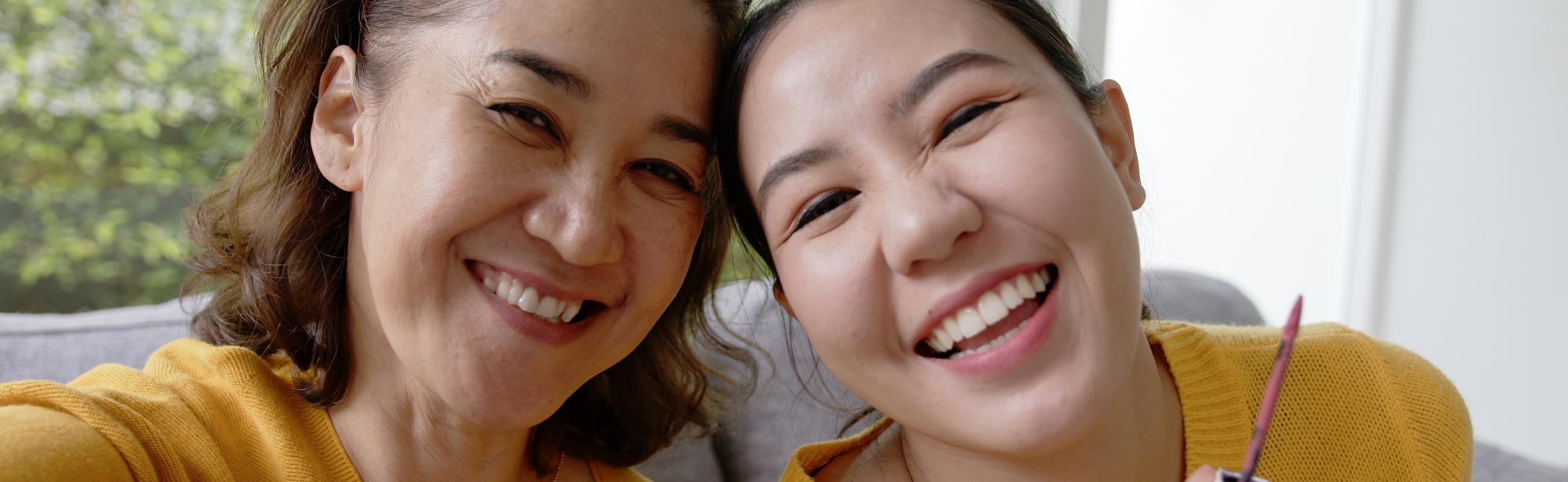 a mother and daughter laugh while painting their nails